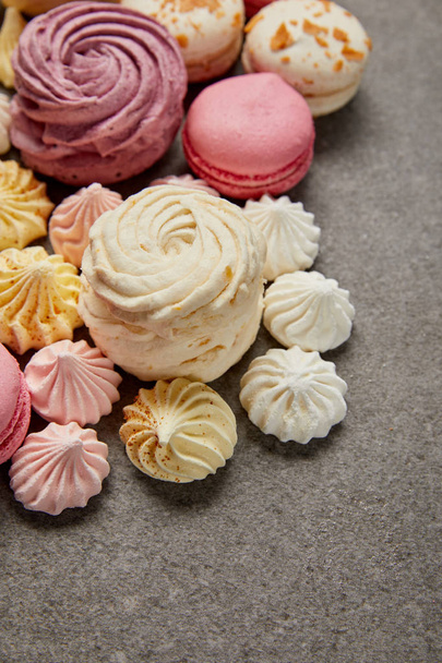 Delicious assorted soft zephyr, small meringues and macaroons on gray background - Fotó, kép