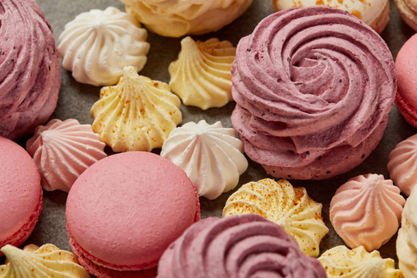 Pink zephyr with small yellow and pink meringues and pink macaroons on gray background - Photo, Image