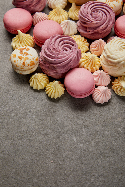 Tasty assorted small meringues, soft zephyr with french macaroons on gray background - Photo, Image