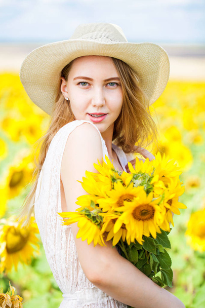 Portrait of a young beautiful girl in a field of sunflowers - Foto, Imagen