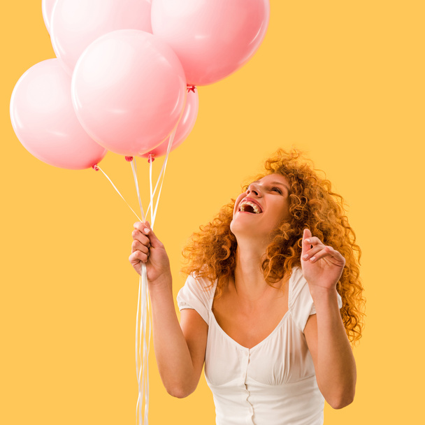excited beautiful redhead woman with pink balloons isolated on yellow - Foto, Imagem