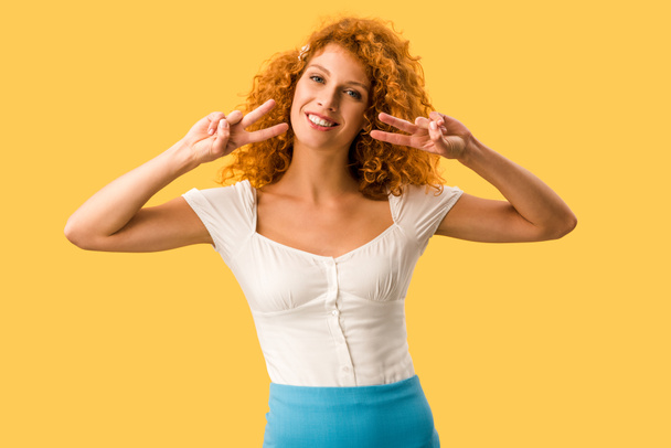 cheerful woman with red hair showing peace symbols isolated on yellow - Foto, immagini