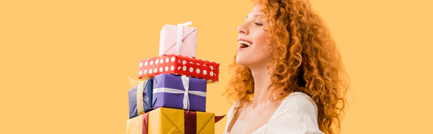 rire rousse fille tenant des cadeaux isolés sur jaune
 - Photo, image