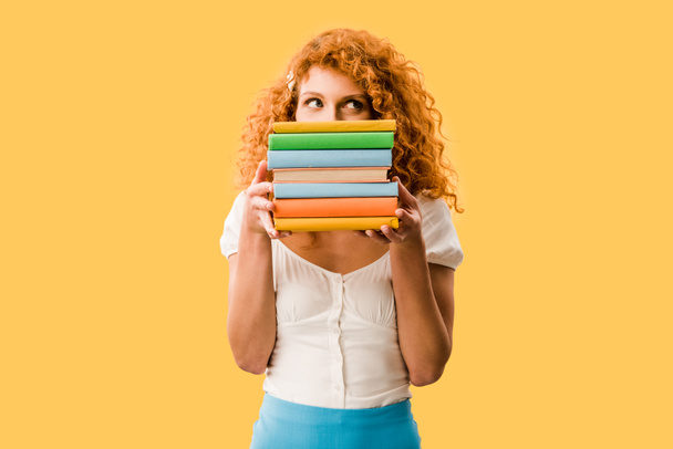 atractiva estudiante femenina sosteniendo libros aislados en amarillo
  - Foto, Imagen