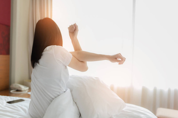 Femme qui s'étire au lit après s'être réveillée, vue de dos. Femme assise
 - Photo, image