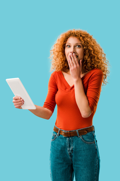 attractive shocked woman using digital tablet isolated on blue - Photo, Image