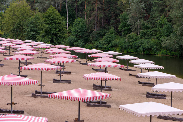 Open red striped parasols and sun loungers on the shore. No vacationers. - Photo, Image