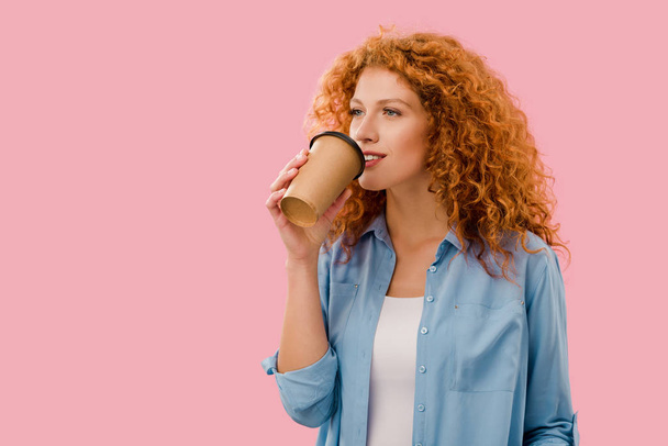 schöne lockige Frau, die Kaffee to go trinkt, isoliert auf rosa - Foto, Bild