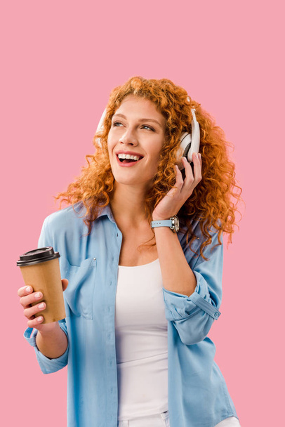 красивая жизнерадостная девушка, слушающая музыку в наушниках на кофе-брейке, Isolated On pink
 - Фото, изображение