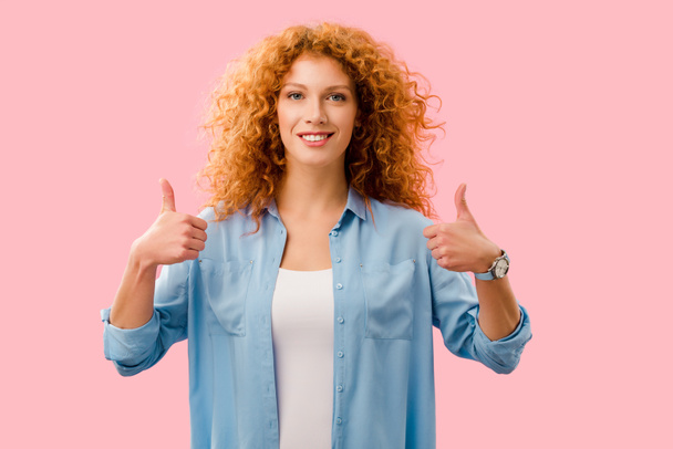 attractive redhead girl showing thumbs up isolated on pink - Фото, зображення