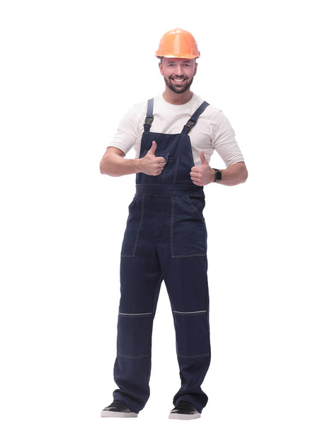 smiling man in overalls showing thumbs up . isolated on white - Foto, afbeelding