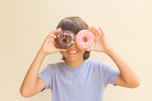 boy making fun with donuts - Foto, Imagen
