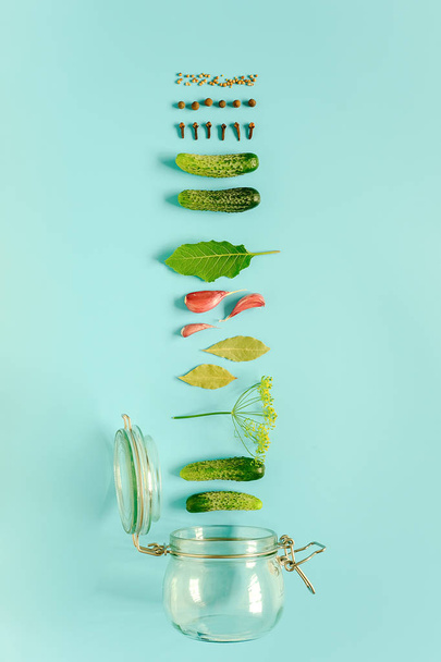 Pepinos en escabeche. Ingredientes para pepinillos marinados y frasco de vidrio sobre fondo azul
.  - Foto, Imagen