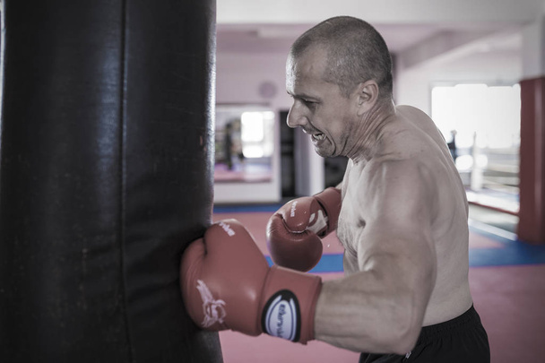 Muay thai bojovník bít boxovací pytel v tělocvičně - Fotografie, Obrázek