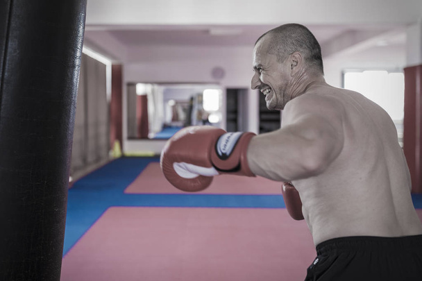 Muay thai luchador golpear la bolsa pesada en el gimnasio
 - Foto, imagen