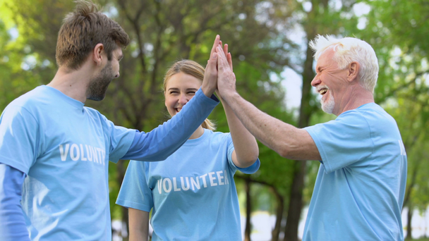 Voluntarios sonrientes dando cinco, gesto de cooperación, proyecto ambiental
 - Metraje, vídeo