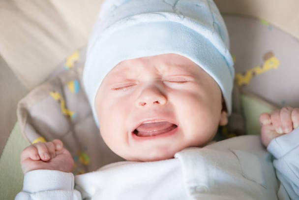 Cute nice little baby boy crying lying  on bed at home. - Photo, Image