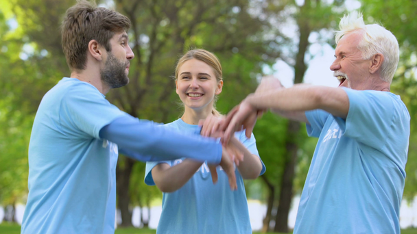 Voluntarios alegres poniendo manos juntas y abrazando, cooperación de trabajo en equipo
 - Metraje, vídeo