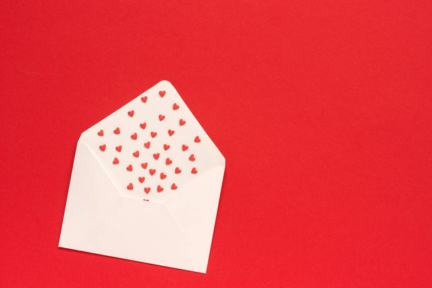 Red Sweets sprinkles candy hearts fly out of white paper envelope - Fotografie, Obrázek