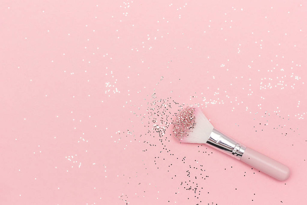 Makeup brush and shiny sparkles on pastel pink background - Foto, afbeelding