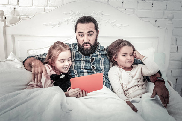 Dad and two kids lying in bed watching movies on tablet - Zdjęcie, obraz