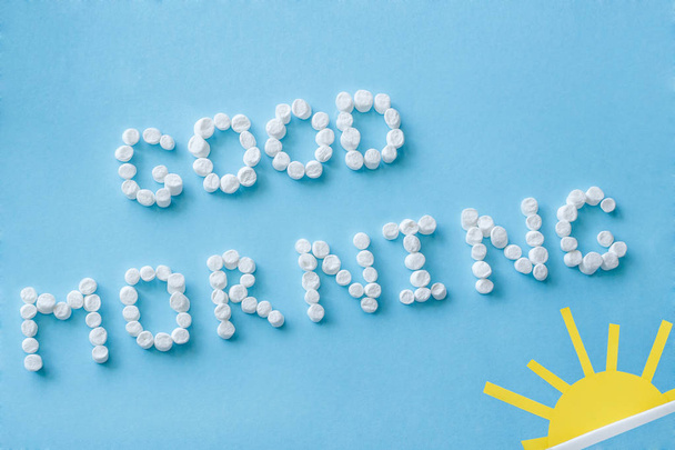 Text Good Morning from marshmallows and figure of rising sun on blue background - Фото, изображение