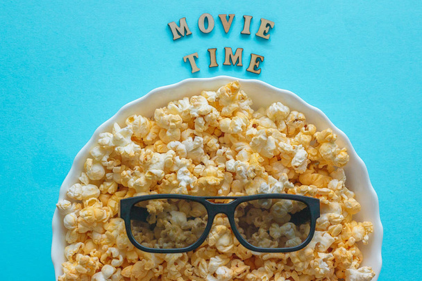 Abstract image of viewer, 3D glasses and popcorn on blue background - Photo, Image