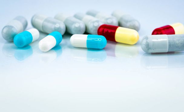 白い背景にカラフルなカプセルの丸薬。製薬業界。他の薬との漢方薬の相互作用.薬学。薬局薬局のコンセプト。青、白、赤、黄色のカプセル錠剤. - 写真・画像