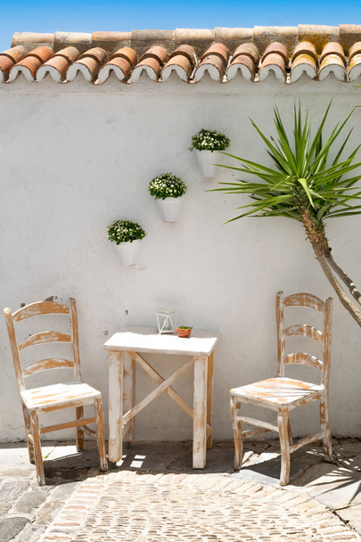 スペイン南部の通りの椅子とテーブル。青空の晴れた日に - 写真・画像