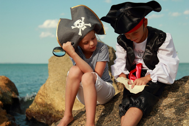 Beautiful young kids pirate boy and girl holding a pirate map and a magnifying glass - Фото, зображення