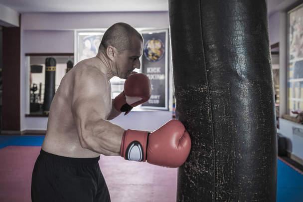 Muay thai luchador golpear la bolsa pesada en el gimnasio
 - Foto, Imagen