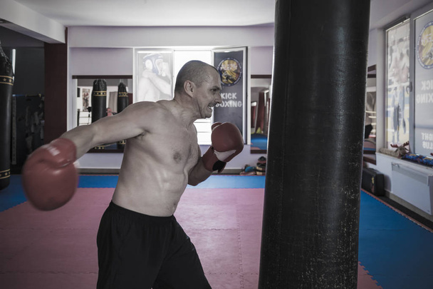 Muay thai luchador golpear la bolsa pesada en el gimnasio
 - Foto, Imagen