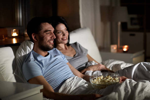 couple with popcorn watching tv at night at home - Foto, imagen