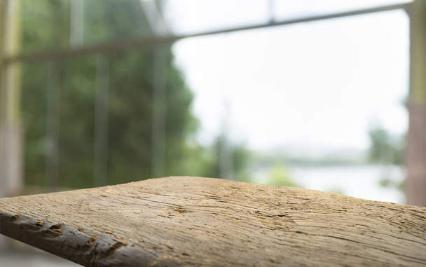 Порожній дерев'яний стіл зверху на розмитій шторі з видом на вікно зеленим з фону саду дерева. Для дисплея продукту монітора або візуального планування ключа дизайну
 - Фото, зображення