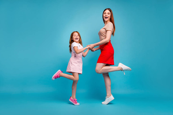 Photo of foxy little lady and her mom holding hands wear casual clothes isolated blue background - Фото, зображення