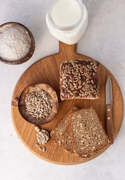 Loaf of wholegrain rye bread with seeds on a wooden cutting board. - Photo, image