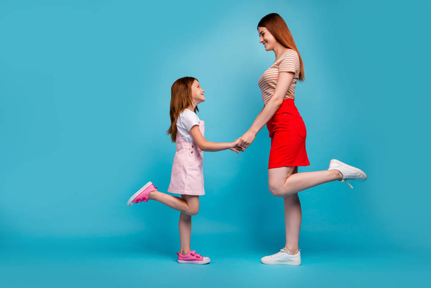 Photo of foxy little lady and mom holding hands looking eyes wear casual clothes isolated blue background - Fotó, kép