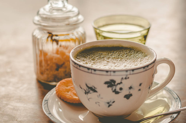 green tea matcha soy latte in a china cup with brown sugar and a glass of water on the side - Foto, imagen