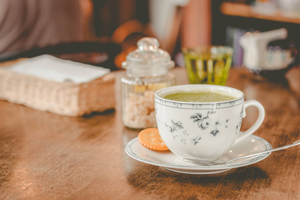 zelený čaj matča sojové Latte v porcelánovém šálku s hnědým cukrem a sklenkou vody po boku - Fotografie, Obrázek