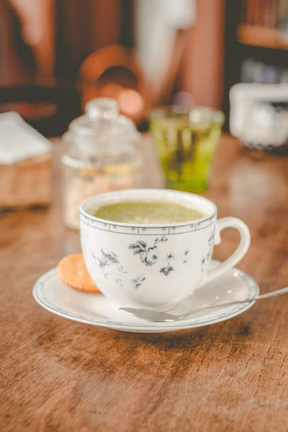 zelený čaj matča sojové Latte v porcelánovém šálku s hnědým cukrem a sklenkou vody po boku - Fotografie, Obrázek