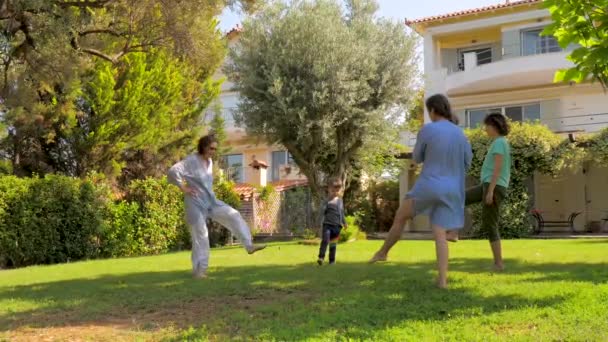 Τρεις γενιές διασκεδάζουν ενώ κάνουν ασκήσεις στο πράσινο γρασίδι στον κήπο. Οι ενήλικες και τα παιδιά νοιάζονται για την υγεία τους. Κάνοντας γυμναστική γιόγκα στη βίλα κοντά στη θάλασσα - Πλάνα, βίντεο