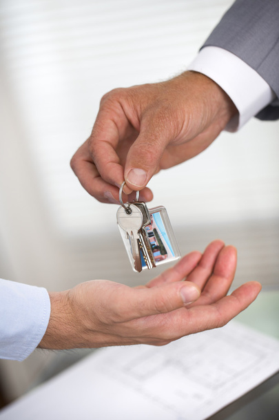 El hombre de negocios está entregando una llave de la casa a un hombre de casa nueva
 - Foto, imagen