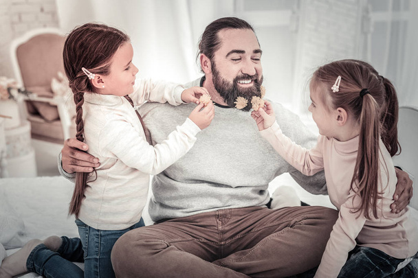 Two girls putting flowers into fathers beard - Photo, Image