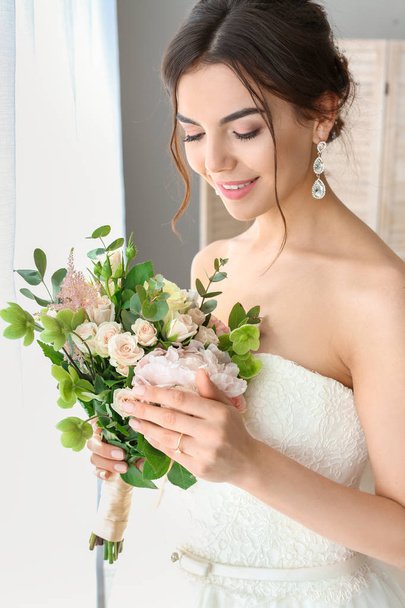 Beautiful young bride with bouquet of flowers at home - Photo, Image