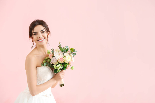 schöne junge Braut mit Blumenstrauß auf farbigem Hintergrund - Foto, Bild