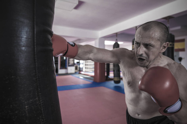 Muay thai harcos ütő az edzőteremben nehéz táska - Fotó, kép