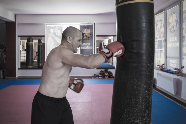 Muay Ταϊλανδός μαχητής χτυπήσει τον βαριά τσάντα στο γυμναστήριο - Φωτογραφία, εικόνα