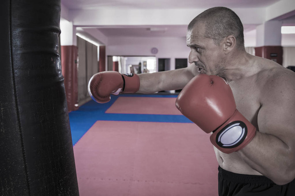 Muay thai fighter hitting the heavy bag in the gym - Фото, зображення