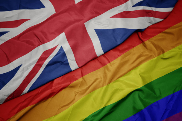 waving colorful gay rainbow flag and national flag of great britain. - Φωτογραφία, εικόνα