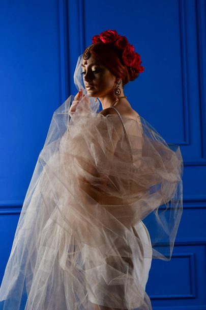 Fashion photo of beautiful girl under white veil and red flowers - Zdjęcie, obraz